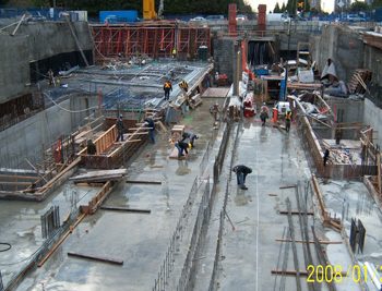 Track slab construction complete. First pour of concrete exterior walls complete. Starter slab for station entrance building under construction.
