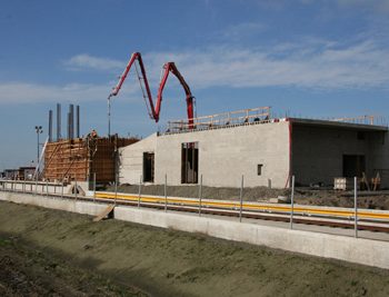 A concrete pump crane delivers concrete to a concrete form.