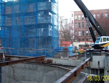 Formerly an entrance to a City parkade, the small brick building in Bill Curtis Plaza was removed to accommodate the remainder of the station footprint. Heavy blue mesh, used to encase the structure, contained dusts and debris during the jackhammering work. Historical timbers from the structure were salvaged.