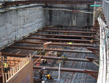 The walls of the excavation are supported by micropile and shotcrete walls. Additional support is provided to the micropile wall through ground anchors and 2 levels of steel bracing. The steel bracing consists of continuous waler beams around the excavation at each level. 22 circular hollow struts across the pit were installed measuring 18 meters long, 450 millimetres in diameter, and weighing approximately 2.5 tonnes each.
